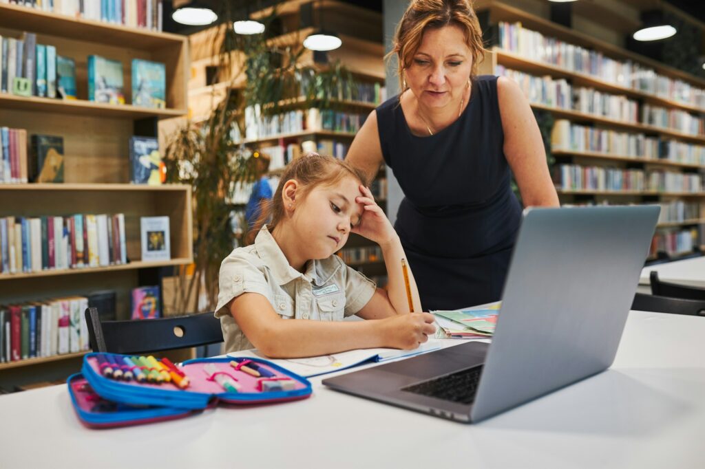 Teacher helping to solve and finish task. Back to school. Child using technology at primary school